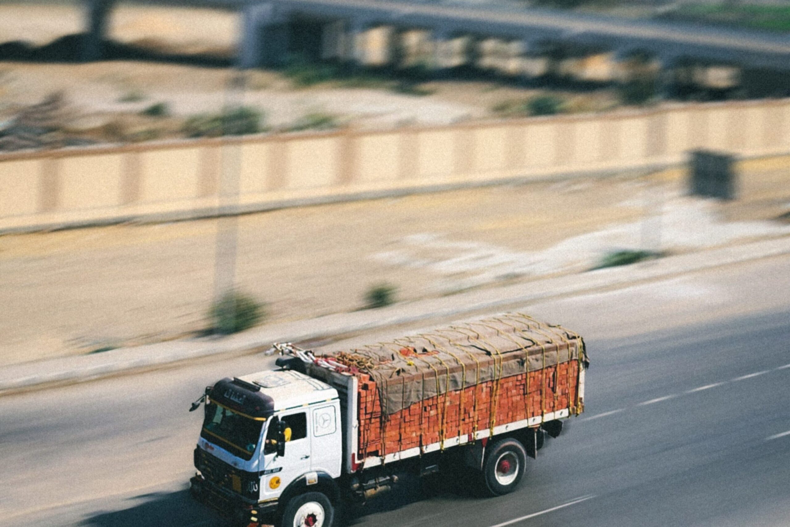 A cargo truck swiftly travels on a highway, emphasizing logistics and speed.